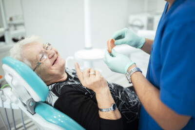 Dentist showing teeth dentures to a senior patient