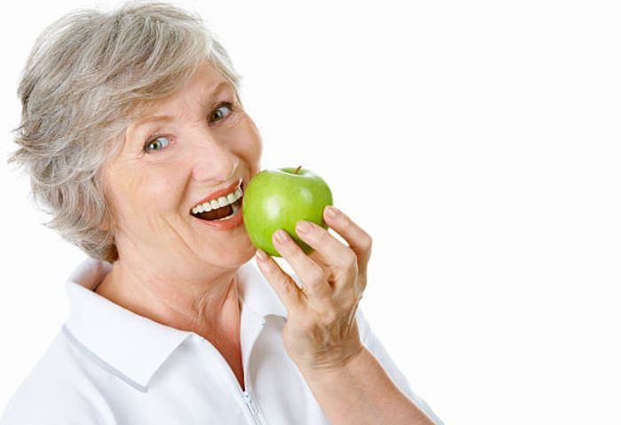 lady eating apple Lady with dentures biting apple